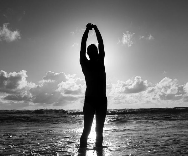 Silhouette of a man stretching at sunrise, symbolizing renewed energy.